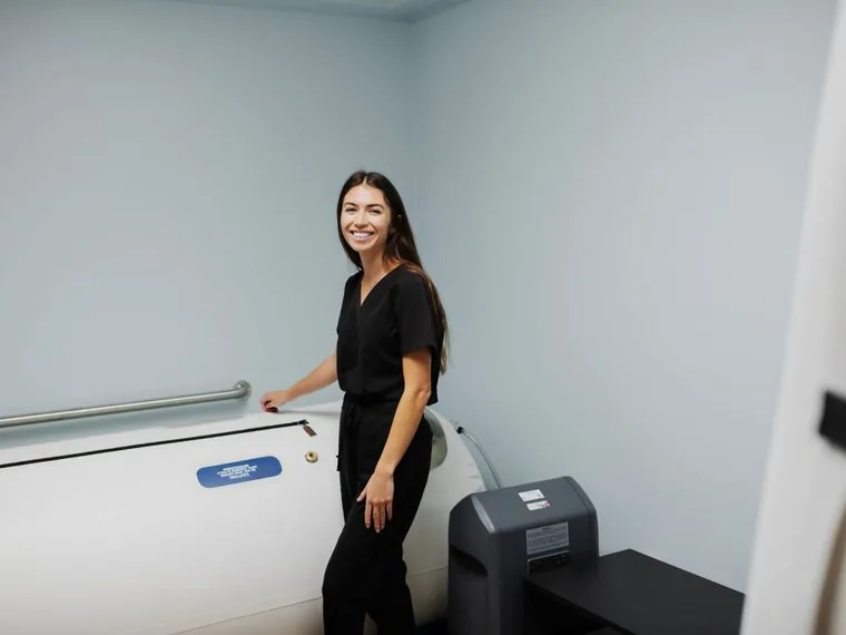 A Koa Clinic staff member beside the hard-shell hyperbaric oxygen chamber